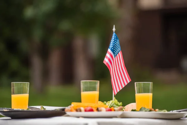 Американский Флаг Возле Апельсинового Сока Размытых Продуктов Открытом Воздухе — стоковое фото