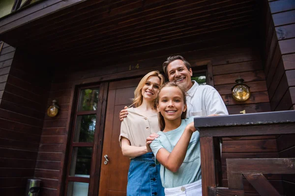 Smiling Girl Looking Camera Parents Hugging Vacation House — Stock Photo, Image