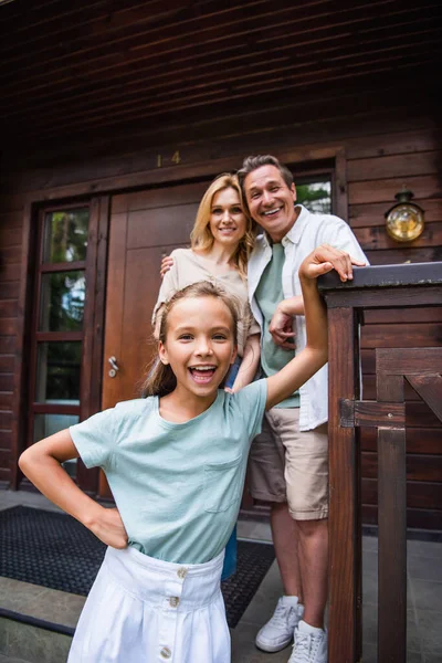 Niño Feliz Mirando Cámara Cerca Los Padres Borrosos Casa Vacaciones — Foto de Stock