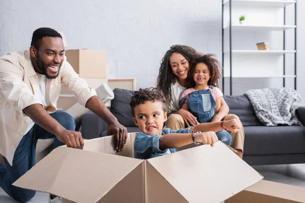 Aufgeregter Afrikanisch Amerikanischer Junge Spielt Karton Neben Glücklichem Papa Neuer — Stockfoto