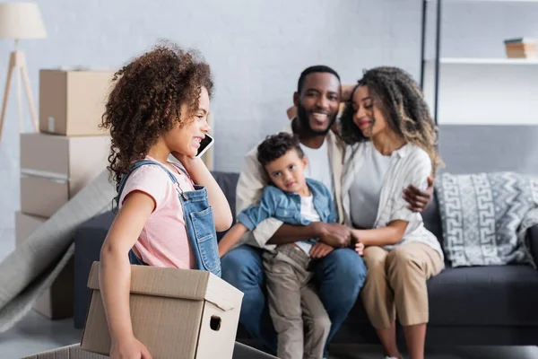 Niño Afroamericano Con Caja Cartón Hablando Teléfono Inteligente Cerca Familia — Foto de Stock