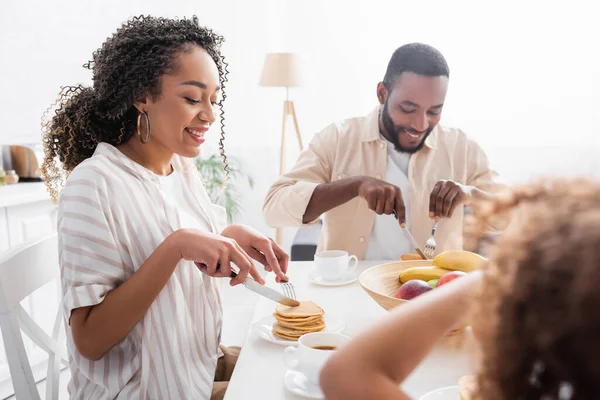 非洲裔美国妇女在与家人共进早餐时边吃煎饼边笑 — 图库照片