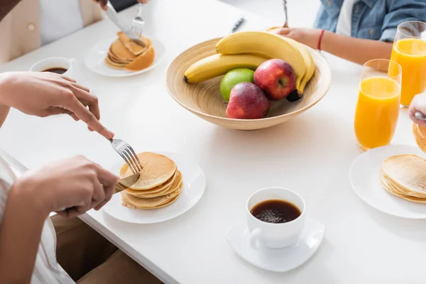 アフリカ系アメリカ人の家族がパンケーキや果物コーヒーやオレンジジュースをテーブルの上で — ストック写真