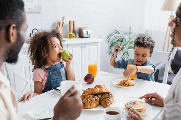 アフリカ系アメリカ人の子供が家族と朝食中にアップルを食べる — ストック写真