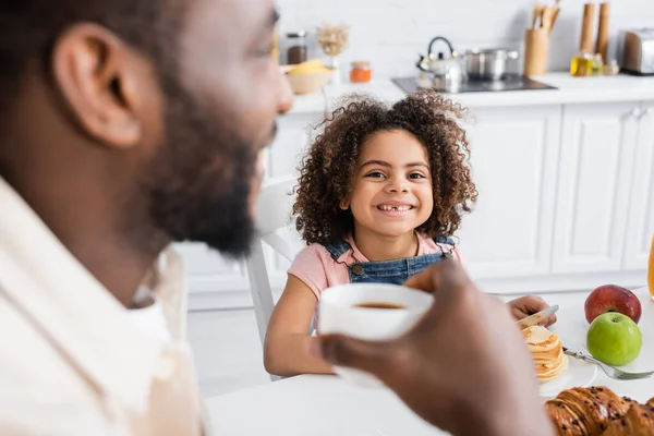 アフリカ系アメリカ人男性が明るい娘と朝食中にコーヒーを飲むのを — ストック写真
