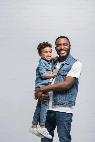 Alegre Africano Americano Hombre Sonriendo Cámara Mientras Holding Hijo Gris — Foto de Stock