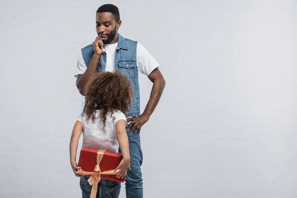 Reflexivo Afroamericano Pie Con Mano Cadera Cerca Hija Con Presente —  Fotos de Stock