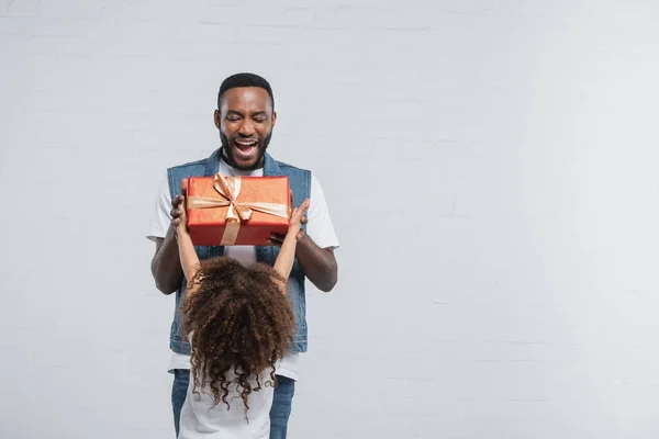 Visão Traseira Menina Apresentando Presente Para Pai Americano Africano Espantado — Fotografia de Stock