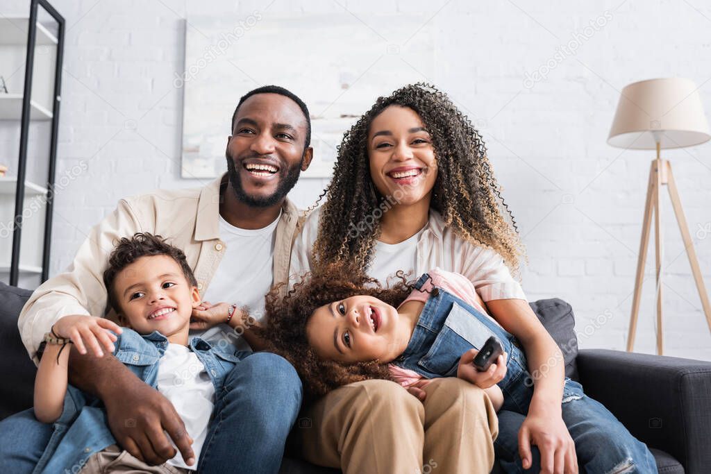 african american family laughing while watching comedy at home