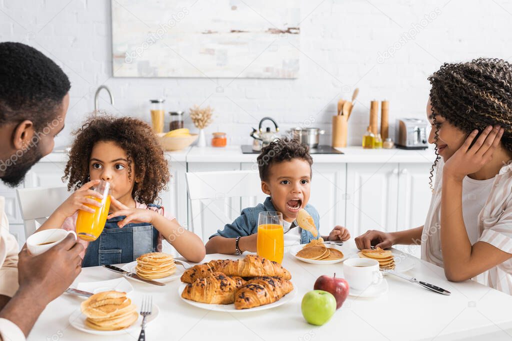 african american children having breakfast with parents in kitchen