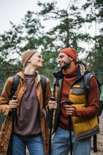 Feliz Pareja Con Mochilas Sosteniendo Bastones Senderismo Mirándose Bosque — Foto de Stock