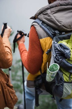 map in backpack of man standing near woman