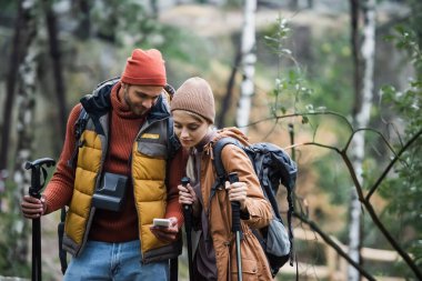 couple looking at smartphone while trekking in woods