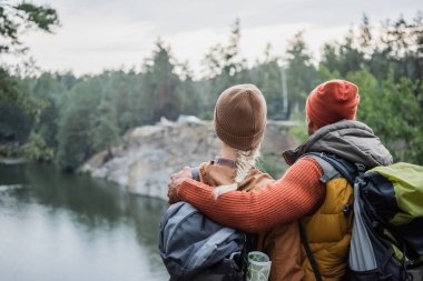 back view of man hugging woman near lake