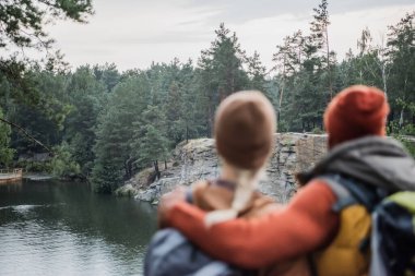 back view of blurred man hugging woman near lake