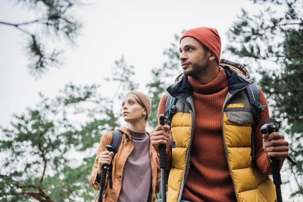 Man Holding Hiking Sticks Standing Blurred Girlfriend Backpack — Stock Photo, Image