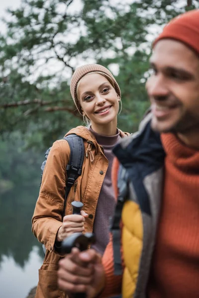 Cheerful Woman Holding Hiking Stick Looking Boyfriend Blurred Foreground — Stock Photo, Image