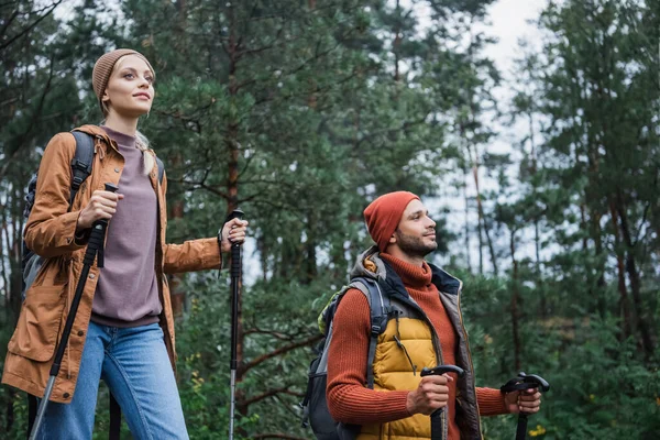 Pleased Woman Holding Hiking Sticks Walking Boyfriend Forest — Stok fotoğraf