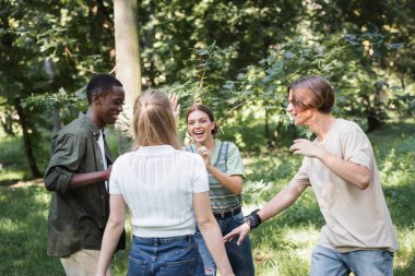 Positive interracial teen friends having fun outdoors  clipart