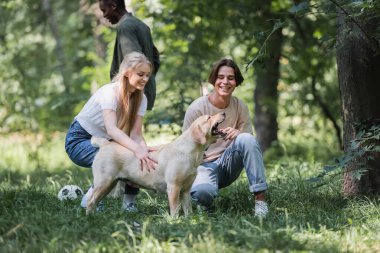 Gülümseyen arkadaşlar, Afrika kökenli Amerikalı bir arkadaşın yanında futbol oynayan av köpeği besliyor. 