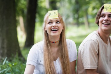 Smiling teenager with sticker playing who i am with friend outdoors  clipart