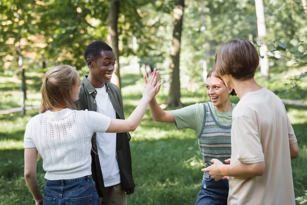 Leende Tonåring Flickor Ger Hög Fem Nära Interracial Vänner Parken — Stockfoto