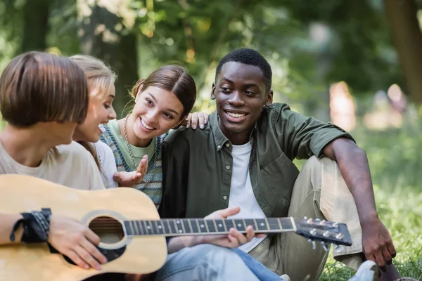 Smiling Teenage Girl Talking Interracial Friends Acoustic Guitar Park — Stock Photo, Image