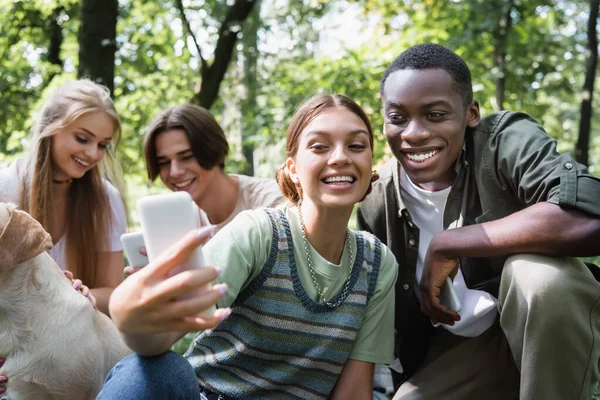 Sonriente Adolescente Tomando Selfie Cerca Afroamericano Chico Amigos Con Retriever — Foto de Stock