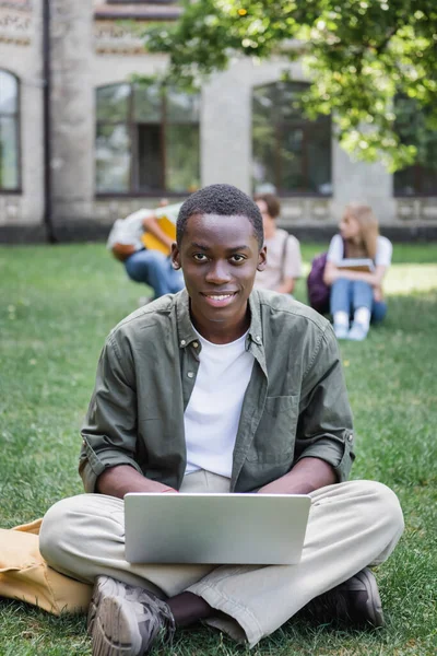 在草坪上用笔记本电脑笑非洲裔美国学生 — 图库照片