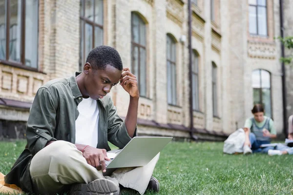 Offensiver Afrikanisch Amerikanischer Student Schaut Auf Laptop Auf Rasen — Stockfoto