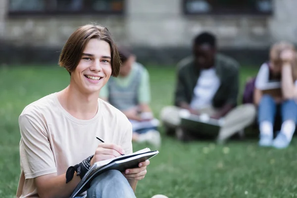 Gelukkig Student Kijken Naar Camera Tijdens Het Schrijven Notebook — Stockfoto