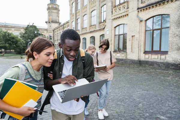 Wieloetniczni Studenci Korzystający Laptopa Pobliżu Budynku Zewnątrz — Zdjęcie stockowe