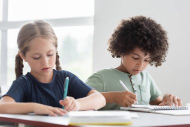 Ders sırasında ırklar arası çocuklar not defterlerine yazıyorlar.