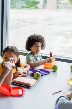 Okuldaki kantinde sandviç yiyen ırklar arası çocuklar.