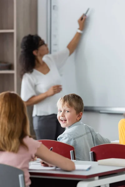 Selective Focus Happy Boy Looking Camera Blurred African American Teacher — Stock Photo, Image