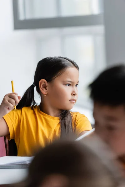 Ernste Asiatische Schulmädchen Halten Stift Während Blick Weg Klassenzimmer — Stockfoto