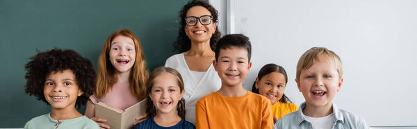 happy african american teacher and multicultural friends smiling at camera, banner