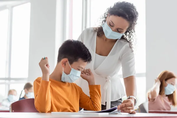 Africano Americano Insegnante Medico Maschera Aiutare Asiatico Scolaro Durante Lezione — Foto Stock