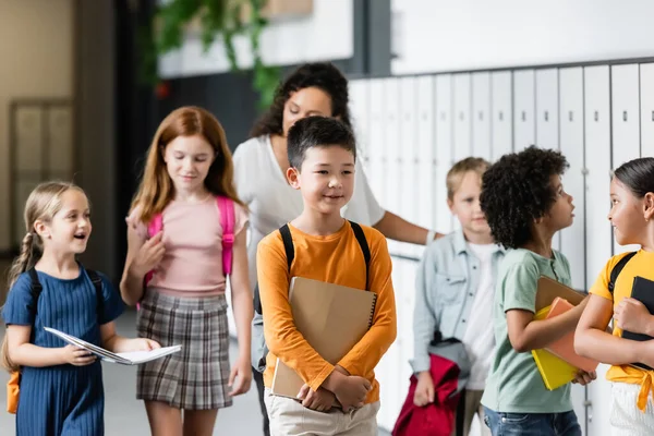 Scolari Multietnici Che Camminano Lungo Corridoio Scolastico Vicino Insegnante Afroamericano — Foto Stock