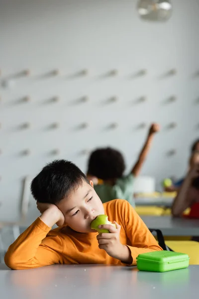 Ledsen Asiatisk Pojke Äter Äpple Skolan Matsal Nära Barnen Suddig — Stockfoto