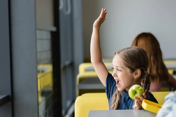 驚きました女の子とともに新鮮なリンゴ手振り手で離れて見ながら学校食堂 — ストック写真