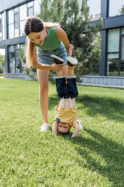 Full Length Happy Mother Supporting Toddler Son Doing Handstand — Stock Photo, Image
