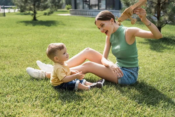 Felice Giovane Madre Possesso Giocattolo Biplano Guardando Allegro Bambino Figlio — Foto Stock