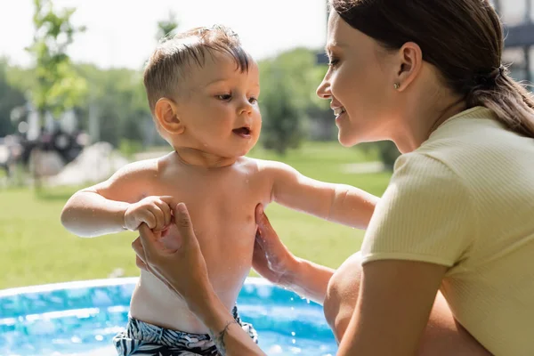 ぼやけて陽気な母親を手に持っています手とともに白人の幼児 — ストック写真