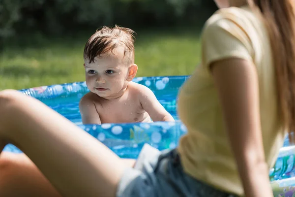 Bambino Ragazzo Seduto Piscina Gonfiabile Vicino Madre Offuscata — Foto Stock