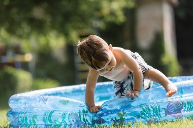 toddler boy climbing over inflatable pool clipart