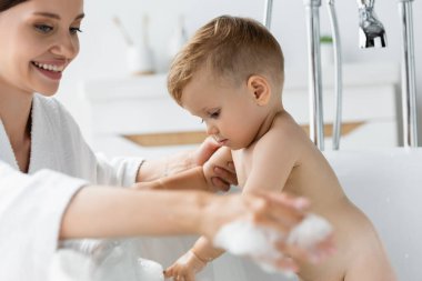 Bornozlu mutlu anne banyo yapan küçük çocuk küvette 