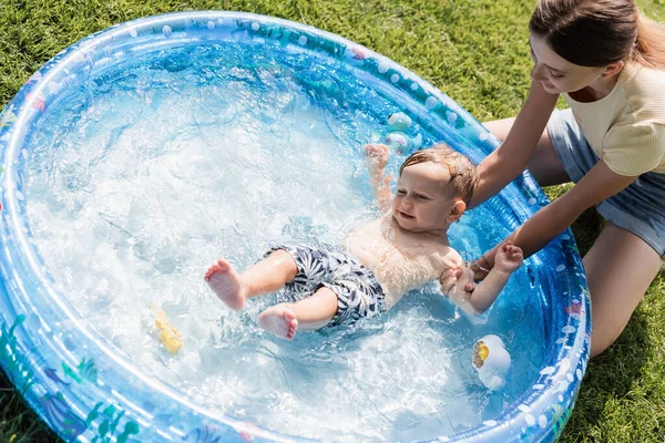 High Angle View Smiling Mother Bathing Shirtless Toddler Son Inflatable — Stock Photo, Image