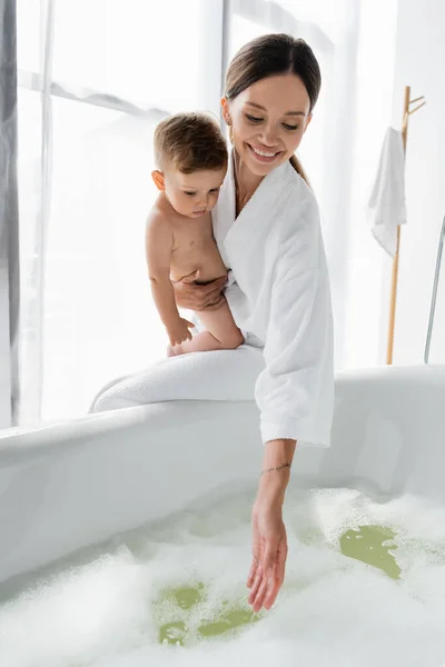 Pleased Tattooed Mother Bathrobe Holding Arms Nude Toddler Son Reaching — Stock Photo, Image