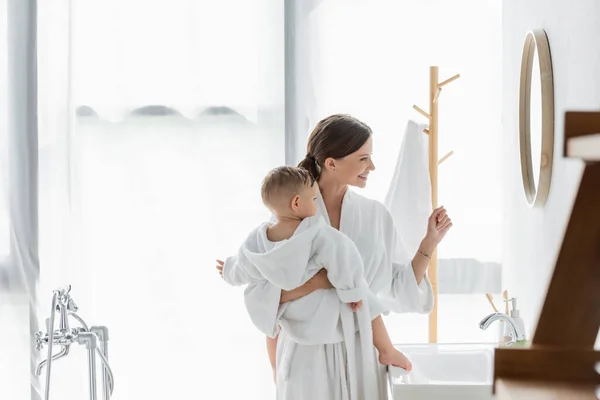 Vista Lateral Madre Alegre Sosteniendo Brazos Hijo Pequeño Mirando Espejo — Foto de Stock